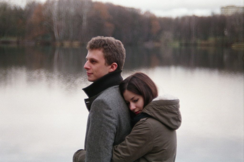 A woman hugging a man near the lake.