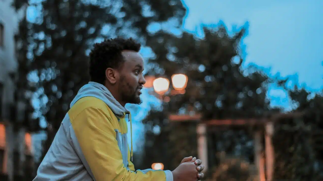 A man in a hoodie standing outdoors at dusk.