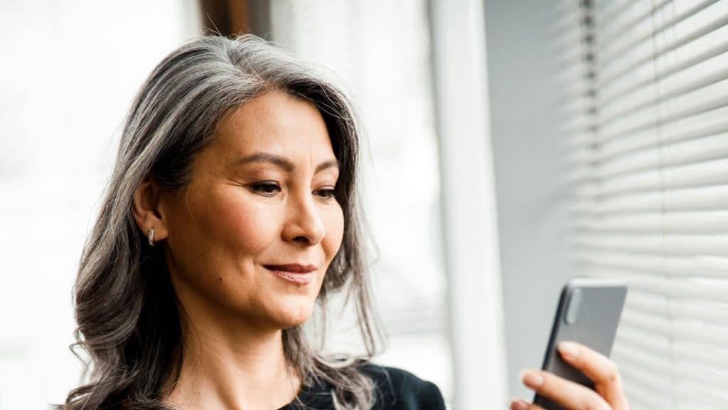 A mature woman looking at her smartphone.