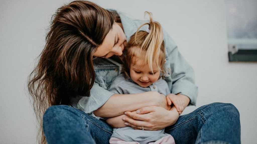 A mother hugging her young child while sitting together.