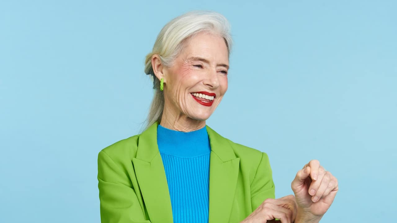 A woman in a green and blue shirt is smiling while taking.