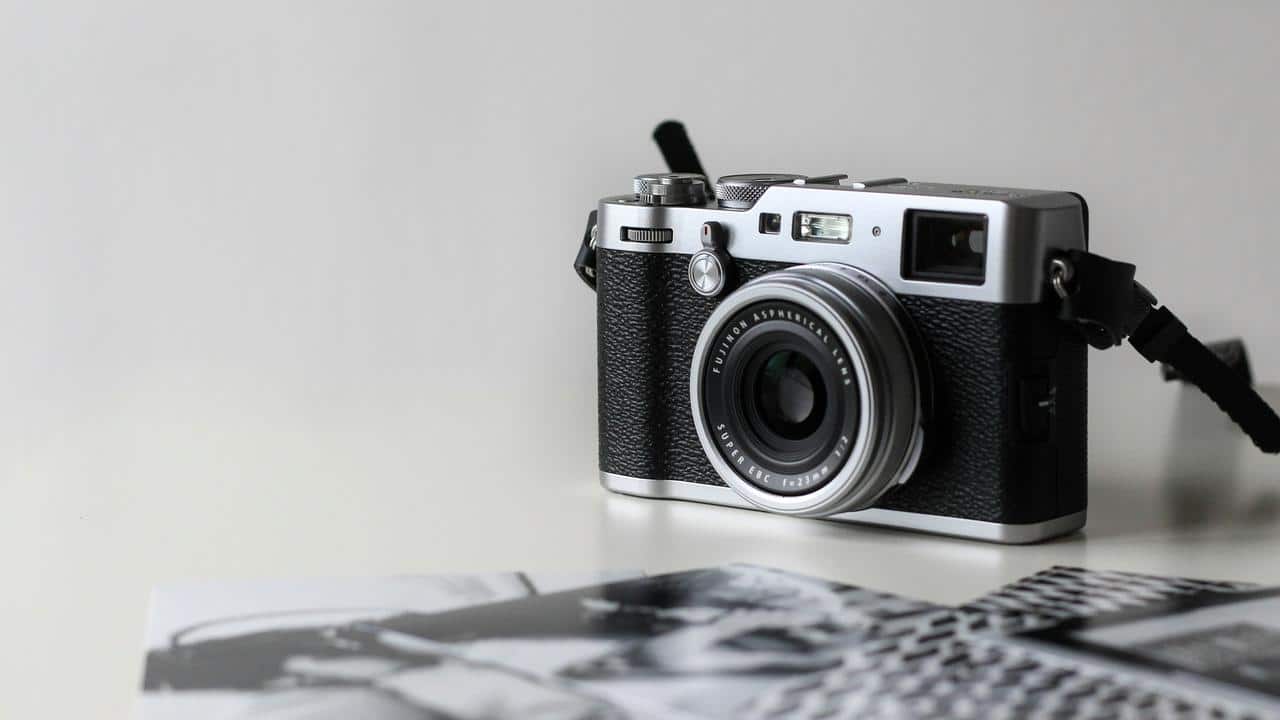 A silver and black retro camera on a white tabletop.