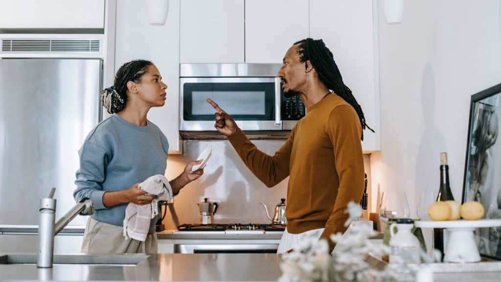 Woman and man arguing in a modern kitchen, man is pointing his finger.