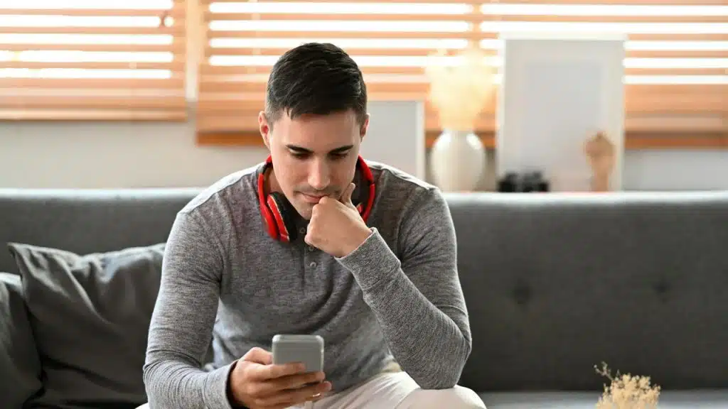 A man looking somber while texting