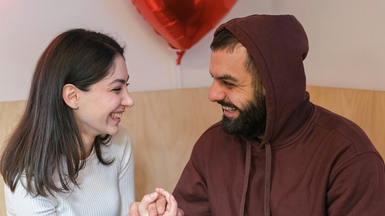 A man and a woman holding hands while sitting together in a restaurant.