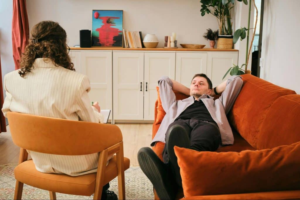 A man resting at the couch and a woman trying to talk to him