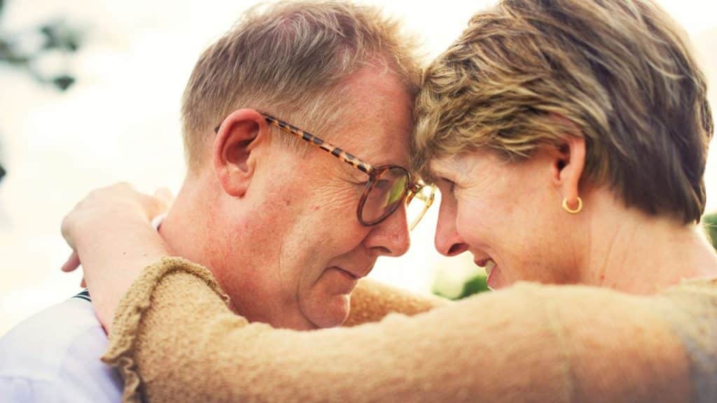 Close-up of an older couple embracing with their foreheads touching.
