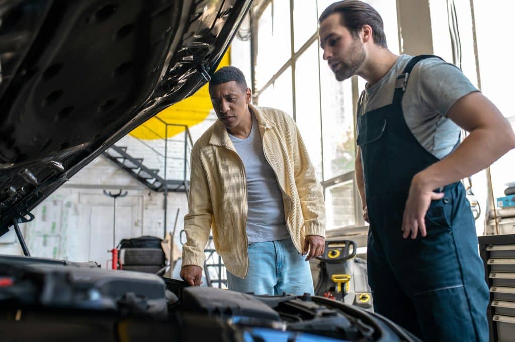 A man talking to a car technician.