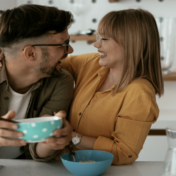 A couple laughing together in the kitchen