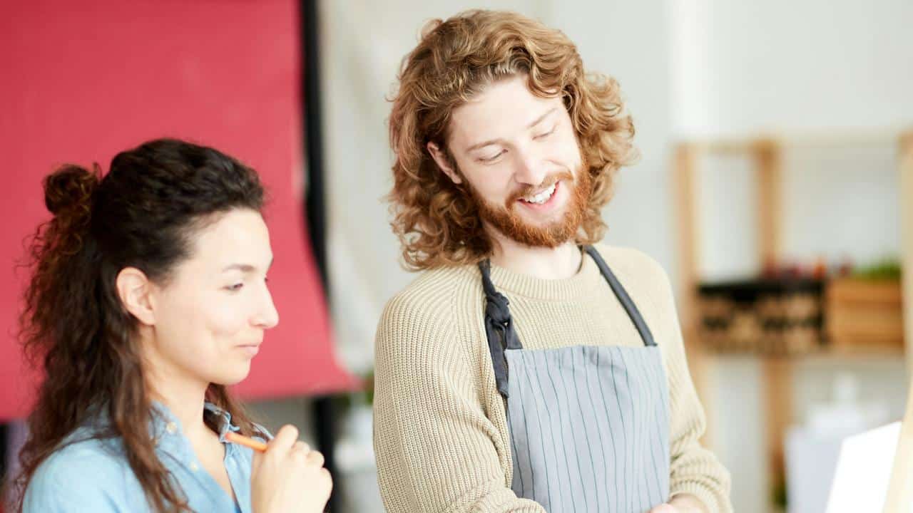 A man and woman smiling while working together on an art project.