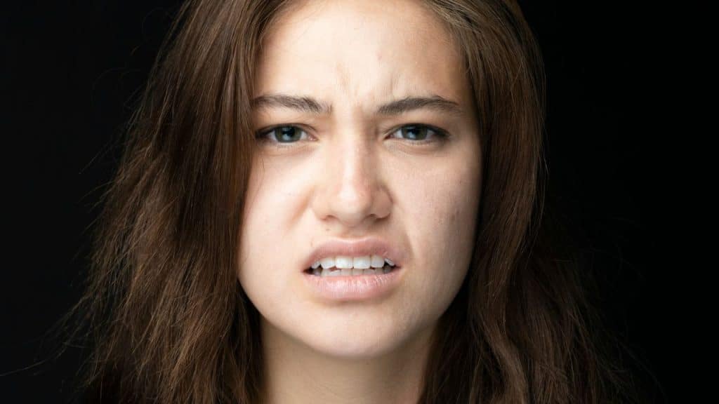 Close-up of a young woman with a scrunched, displeased, or disgusted expression.
