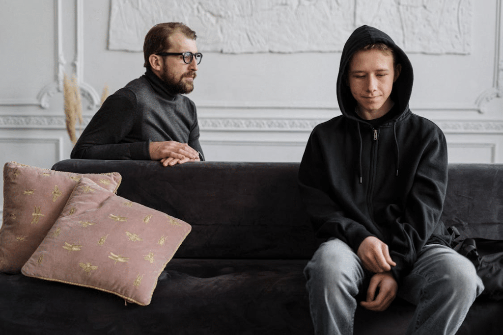 Man in black hoodie sitting on brown couch