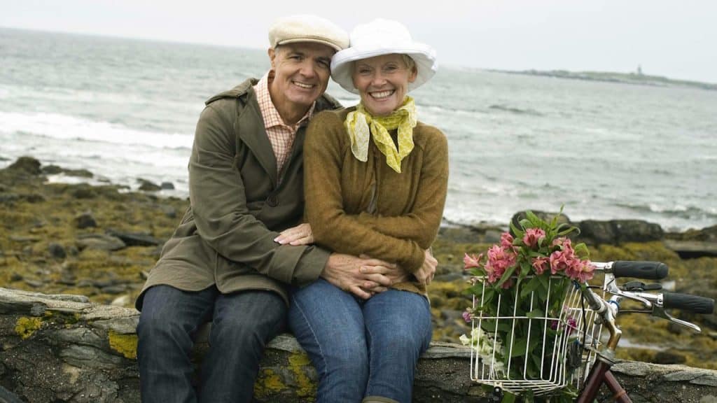 A man and woman sitting on a rock next to a bike.