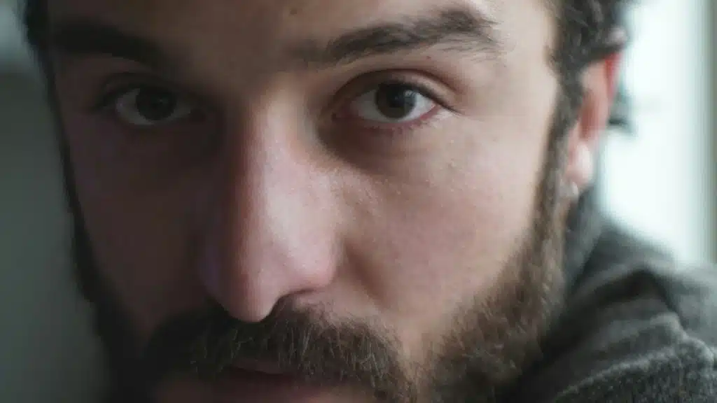 Close-up of a man's face with a beard and intense eyes.