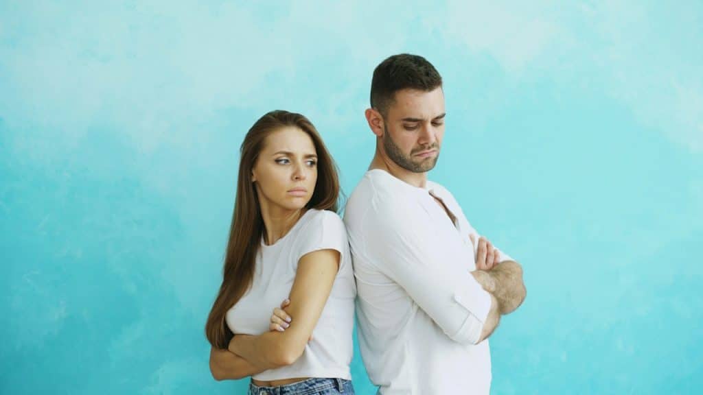 A couple standing with their backs to each other and looking bitter.