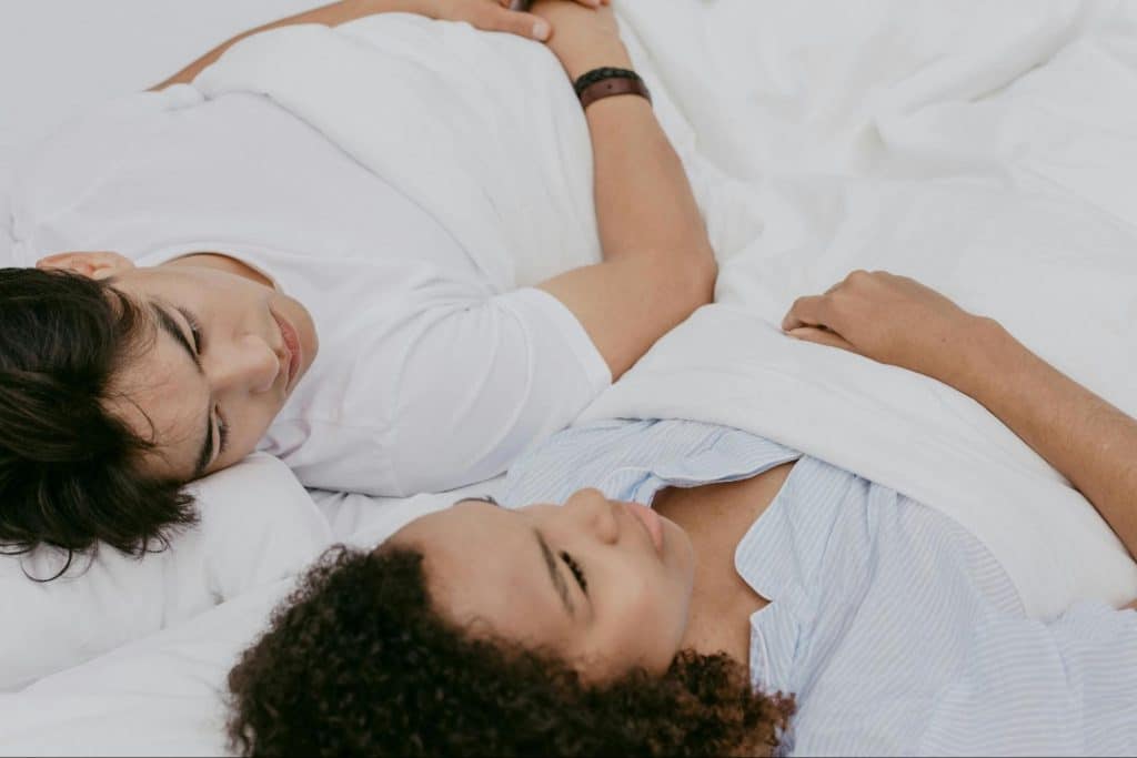 A man and woman talking while lying down at the bed 