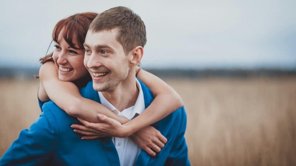 A man and a woman hugging in a field.