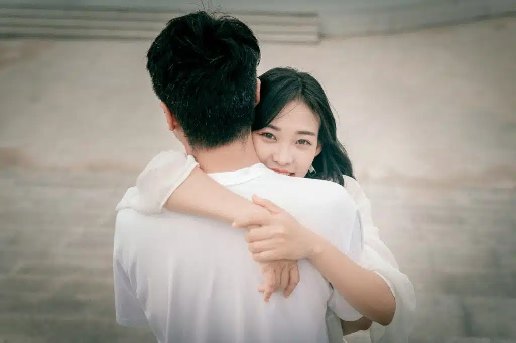 A woman hugging a man and smiling at the camera.