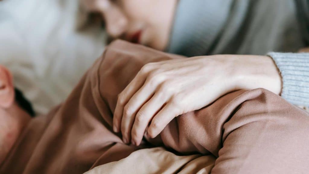 A close-up of a person resting with another’s hand gently placed on their arm.