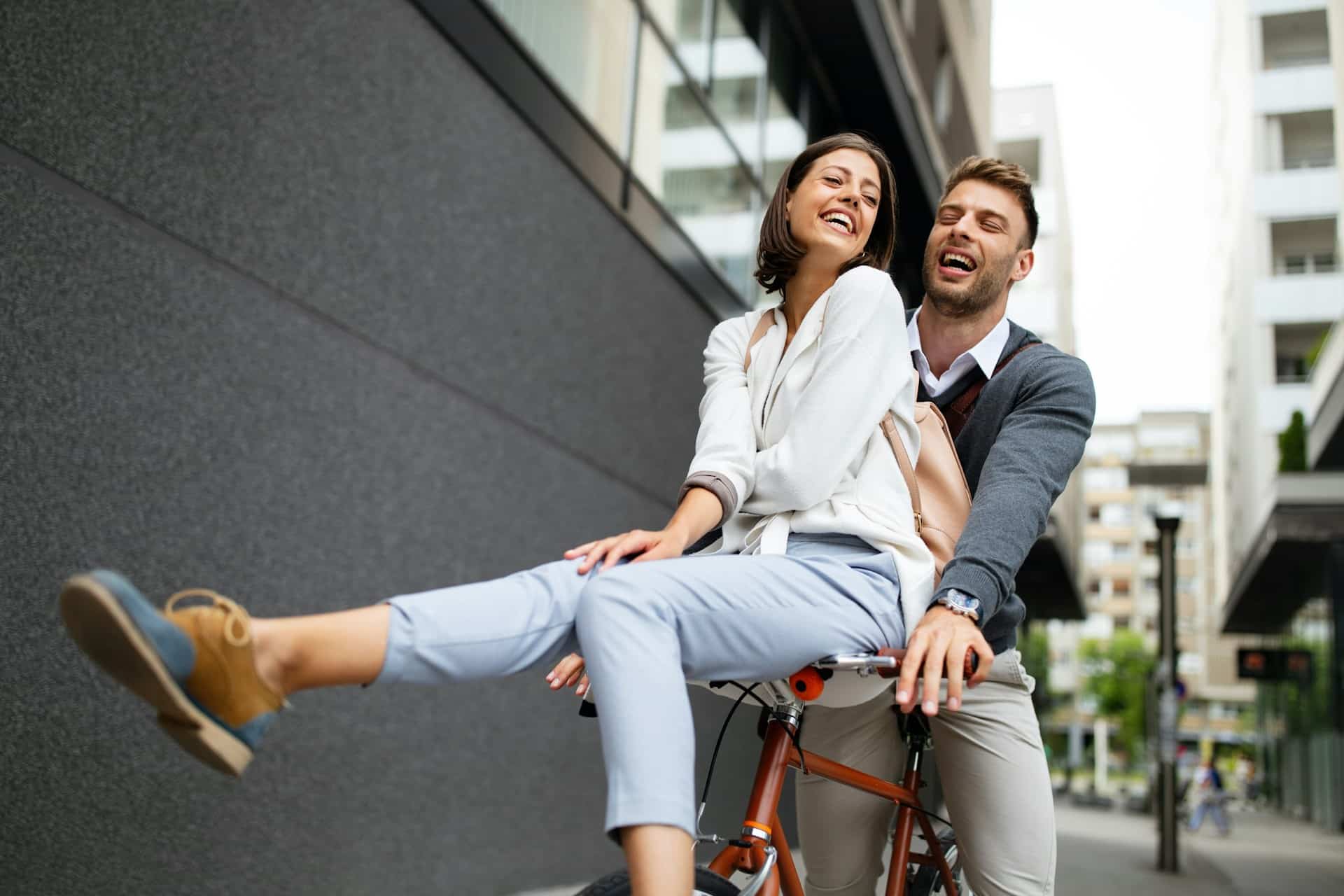 A man and woman having fun while riding a bicycle in the city.