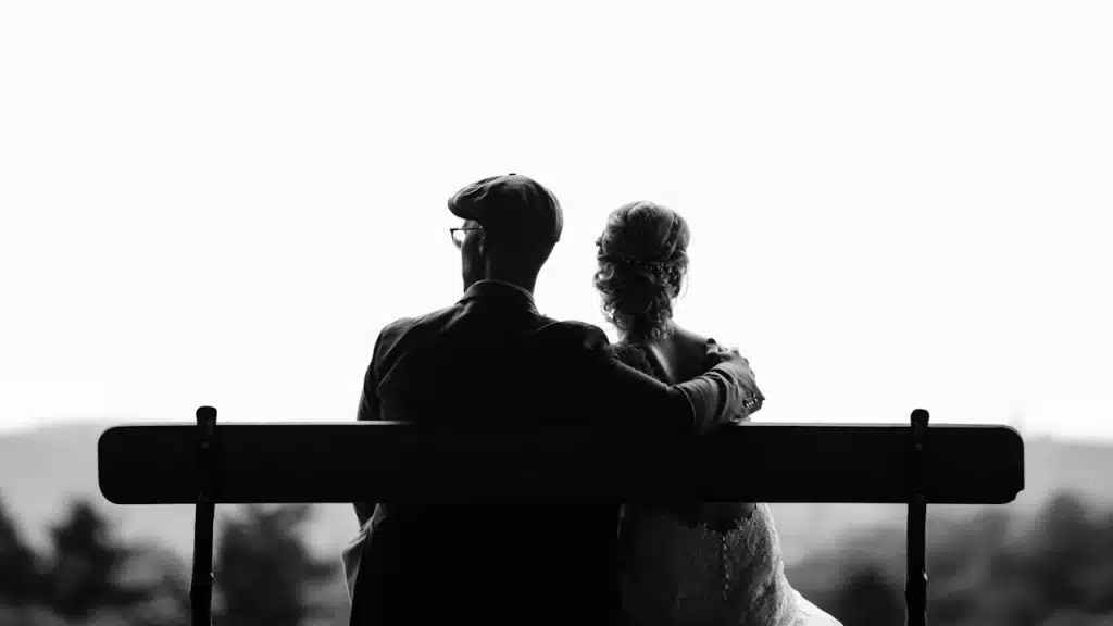 A couple sitting on a bench and looking in opposite directions.
