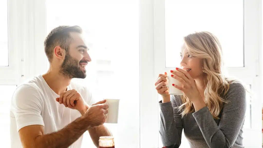 A young loving couple sitting in the kitchen having breakfast talking with each other.