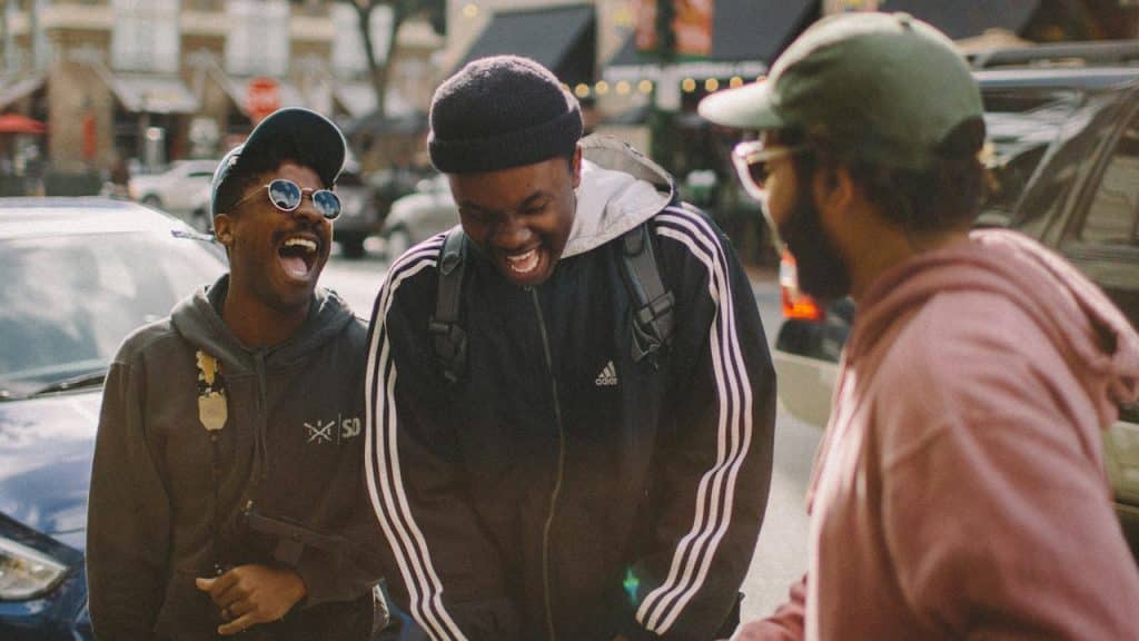A group of friends laughing together while standing in a street.