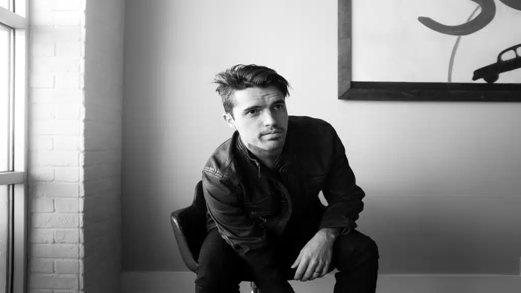 A man sitting down while wearing a leather jacket