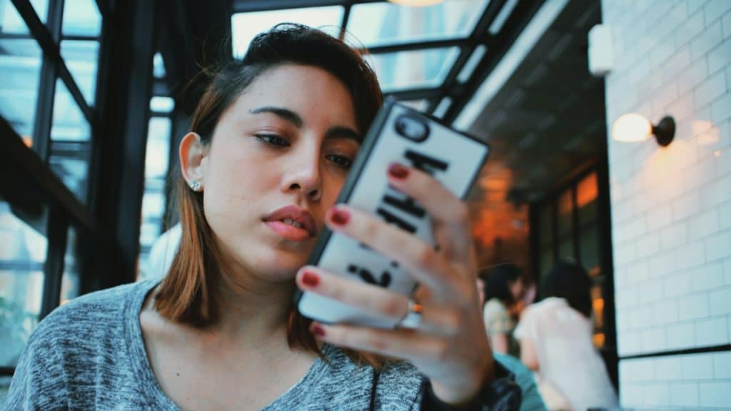 A woman in a gray-and-black sweater holding a white-and-black iPhone case.