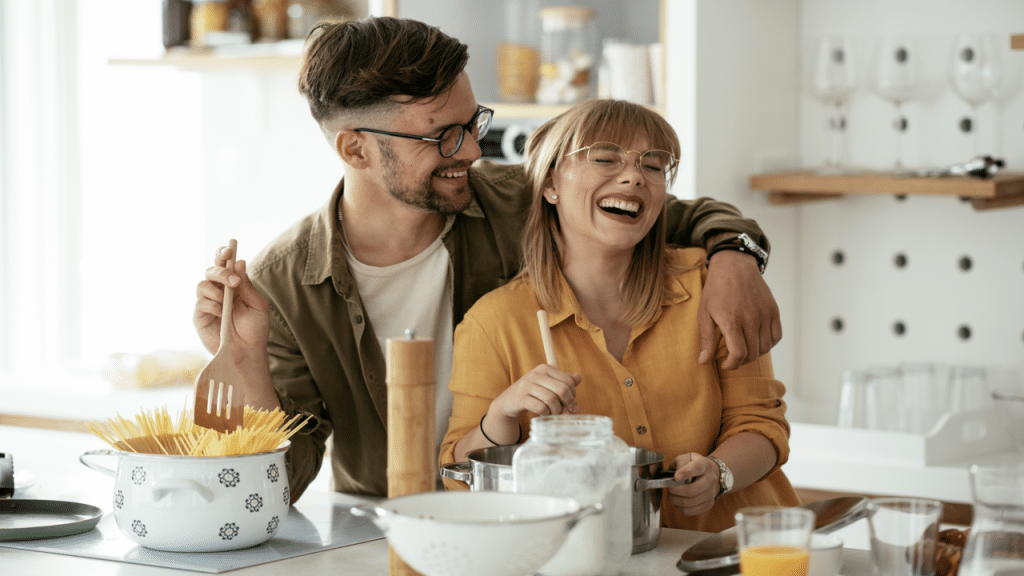 A couple laughing together in the kitchen