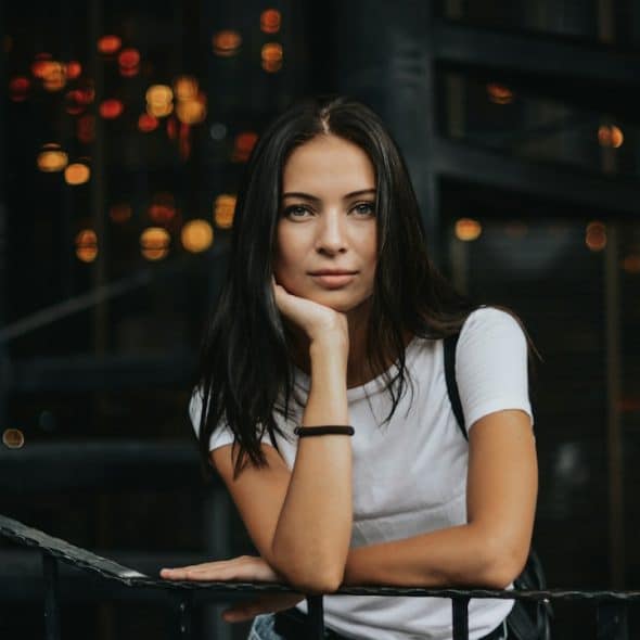 A woman leaning on a black handrail.