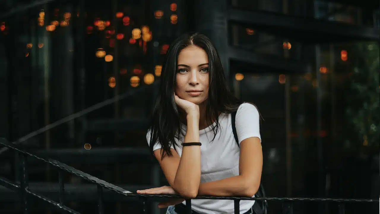 A woman leaning on a black handrail.