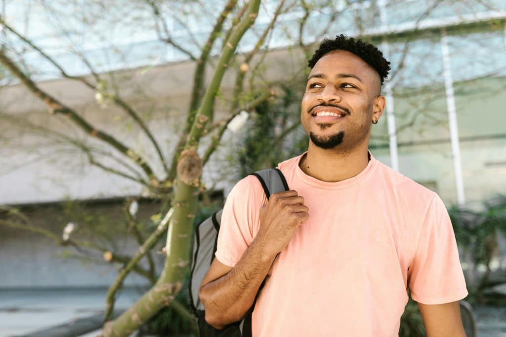 A man smiling while carrying his backpack.