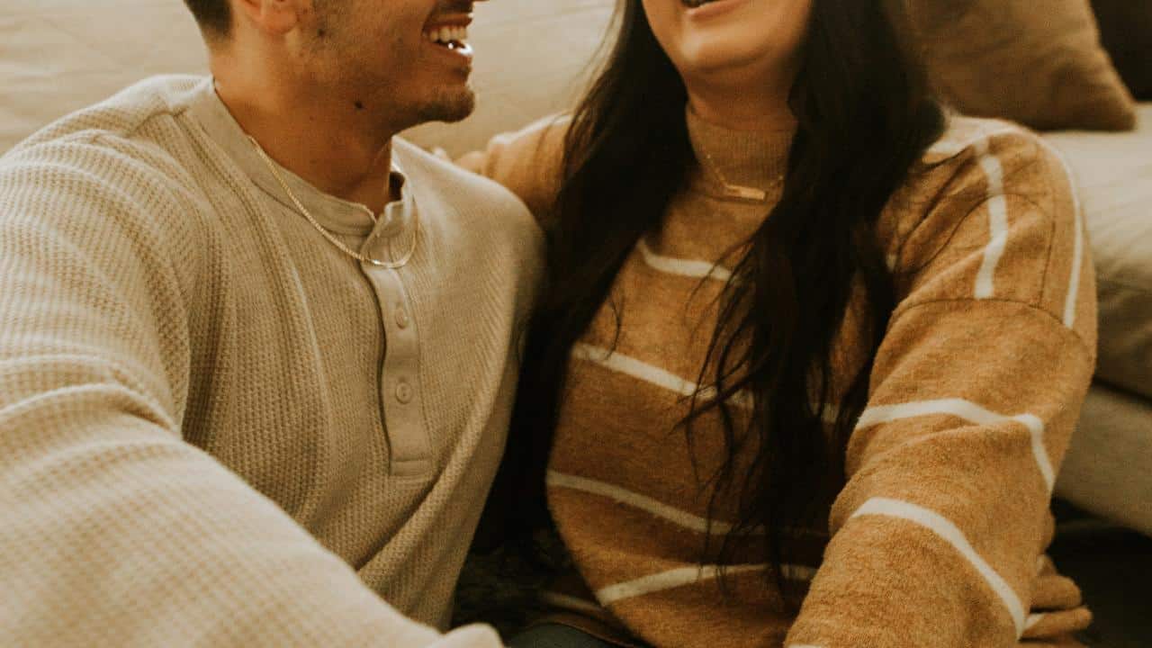 A couple sitting close together and laughing.