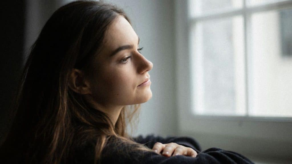 Woman with long dark hair looking intently at a window in profile