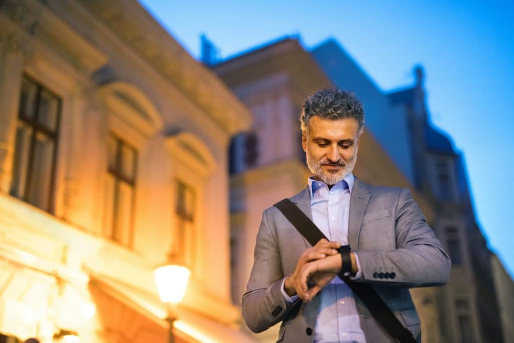 A mature businessman looking at his watch while walking in the city.