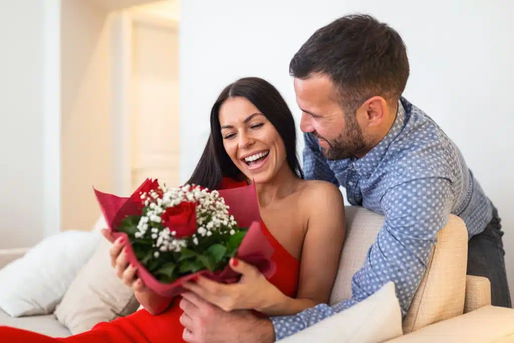 A young woman receiving a bouquet of red roses.