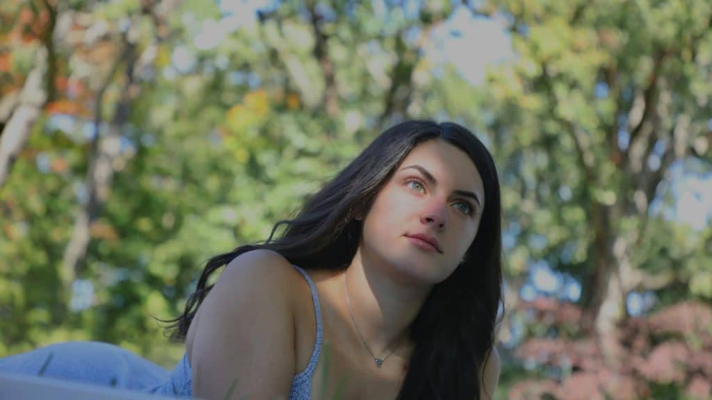 A woman looking pensive while sitting outside.