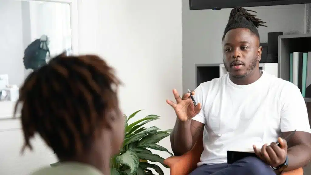 A man sitting in a chair talking to a woman.
