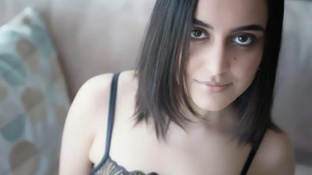 A young woman with short hair wearing a black floral brassiere.