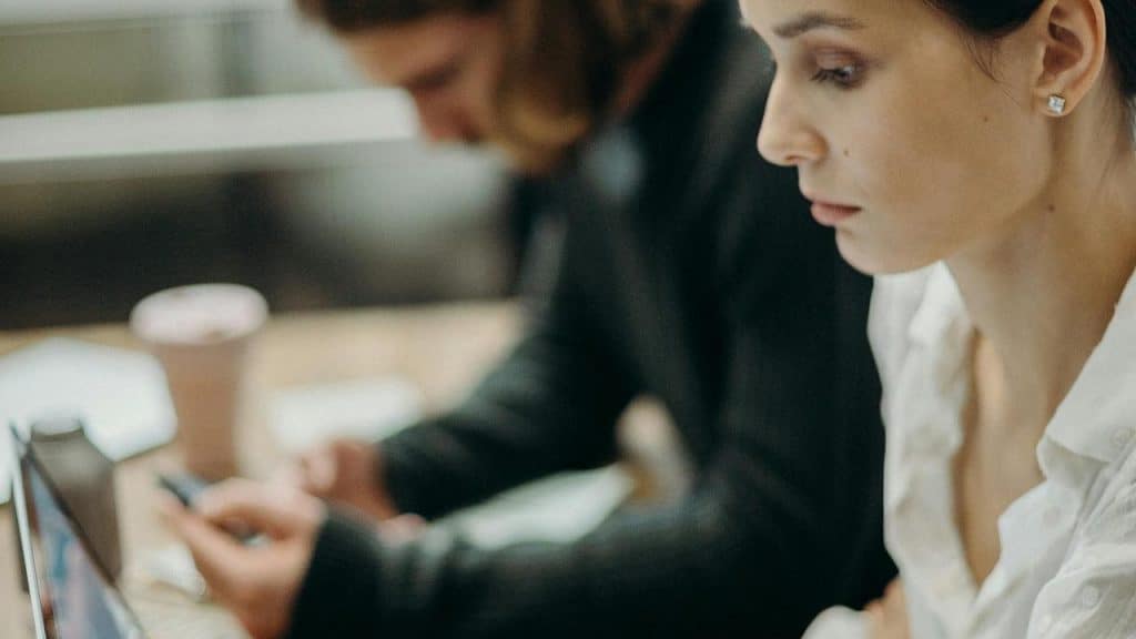 A woman focuses on a laptop at a desk.