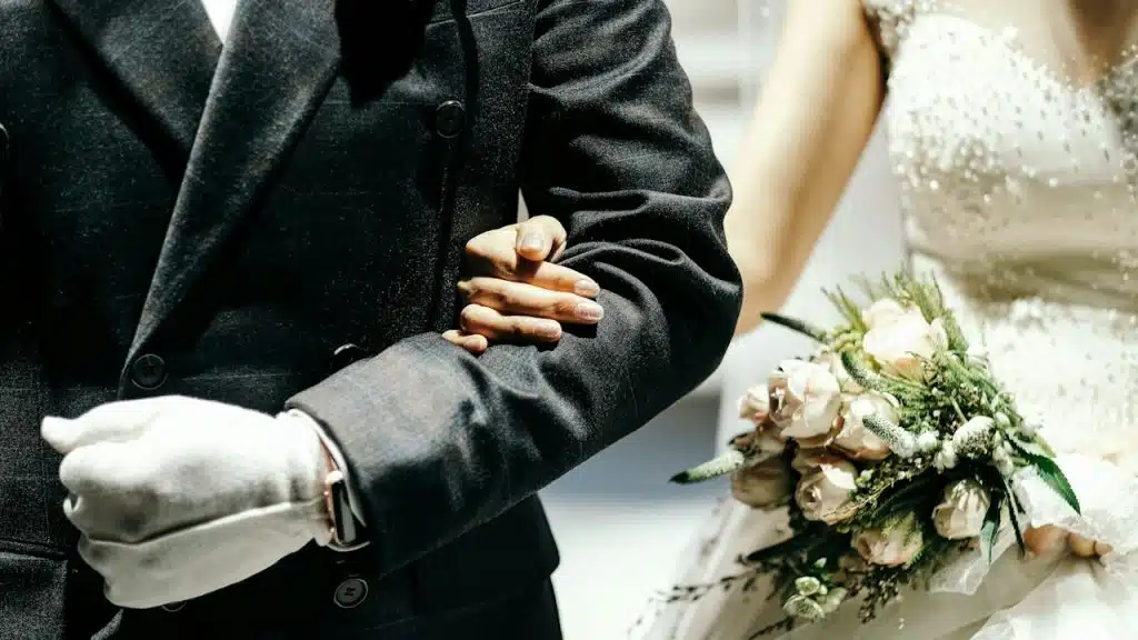A married couple holding hands and a bouquet.