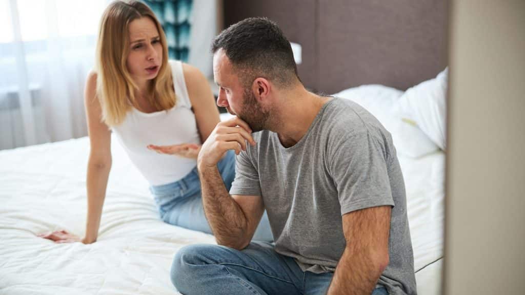 A woman complaining to a man as they sit on a bed.