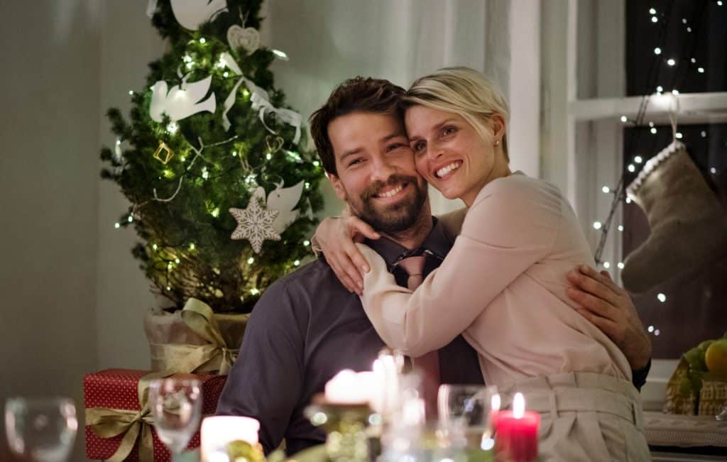 A couple hugging while sitting indoors, celebrating Christmas.
