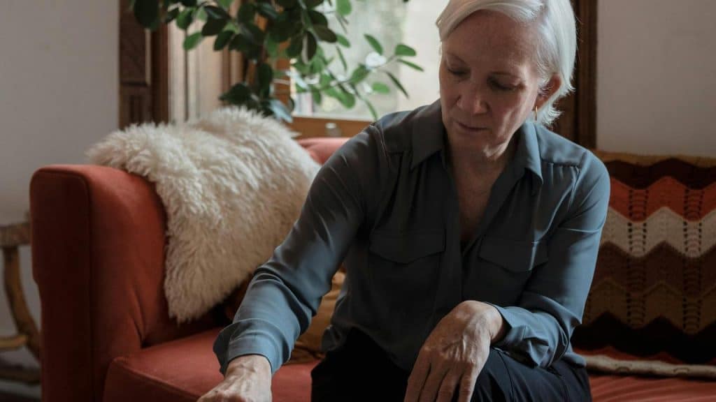 A woman sitting on a couch and looking down thoughtfully.
