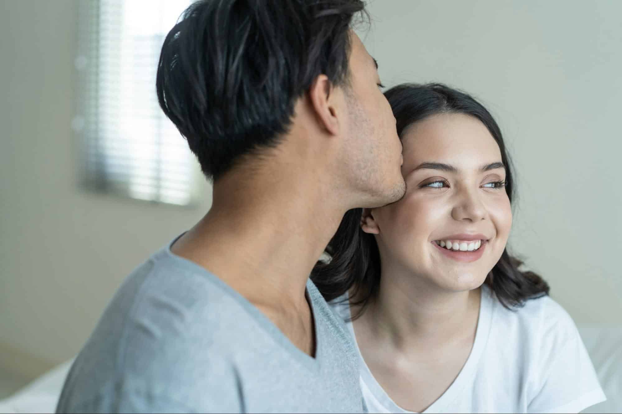 A man kissing a woman’s forehead 