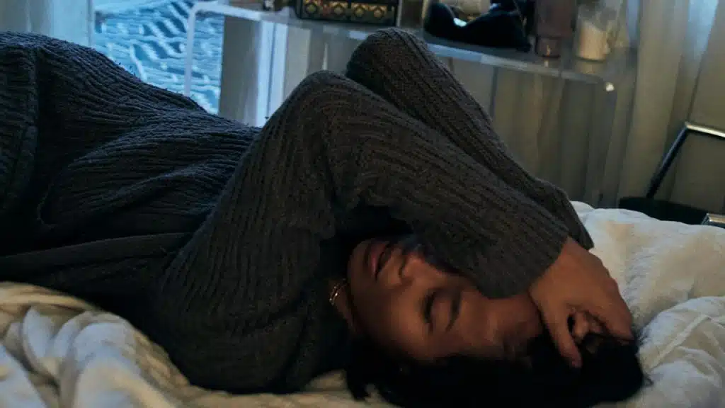A depressed woman lying on a bed.