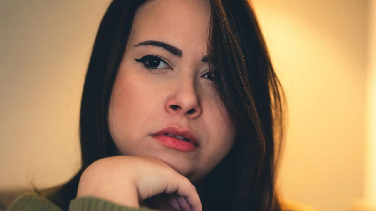 Close-up of a woman looking directly forward with her chin resting on her hand.