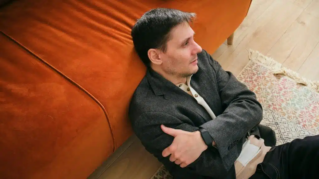 A man sitting on the floor next to a couch.