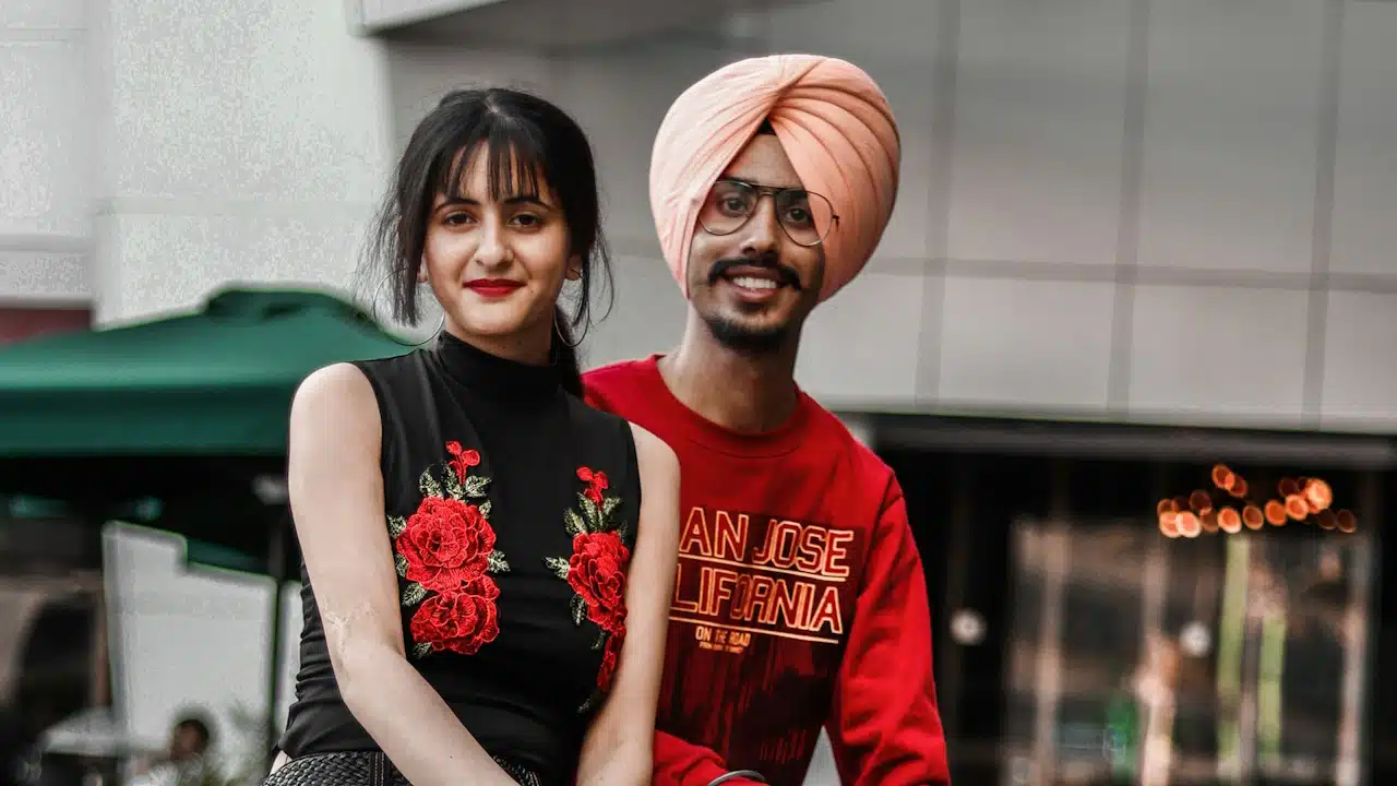 A smiling young couple sitting on a bench outdoors.